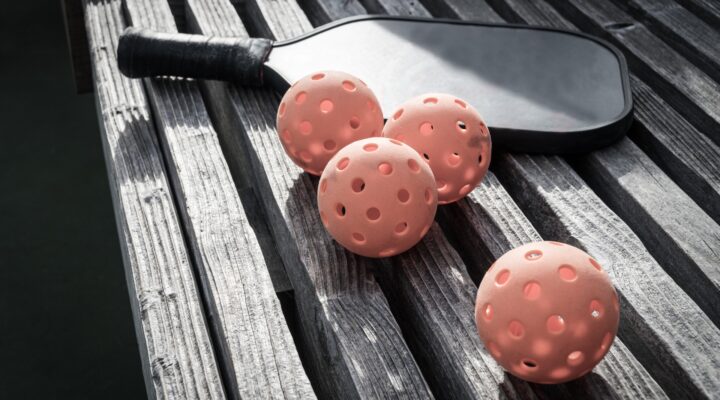 Pickleball paddle and balls on a bench.