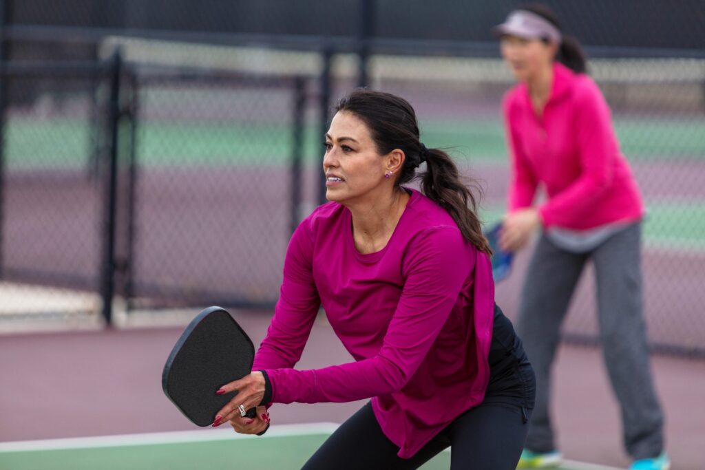 Women on a pickleball court ready to receive the ball.