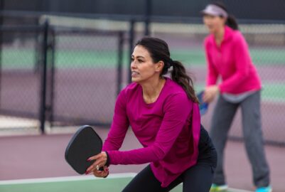 Women on a pickleball court ready to receive the ball.