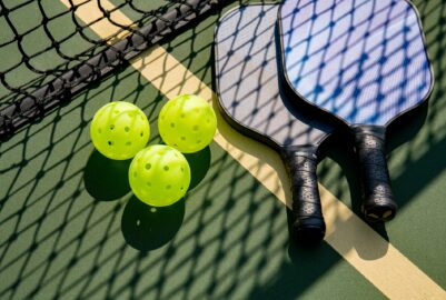 Pickeball paddles and balls on a court.