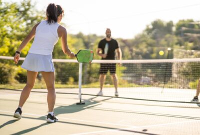 A man and woman playing pickleball outside.