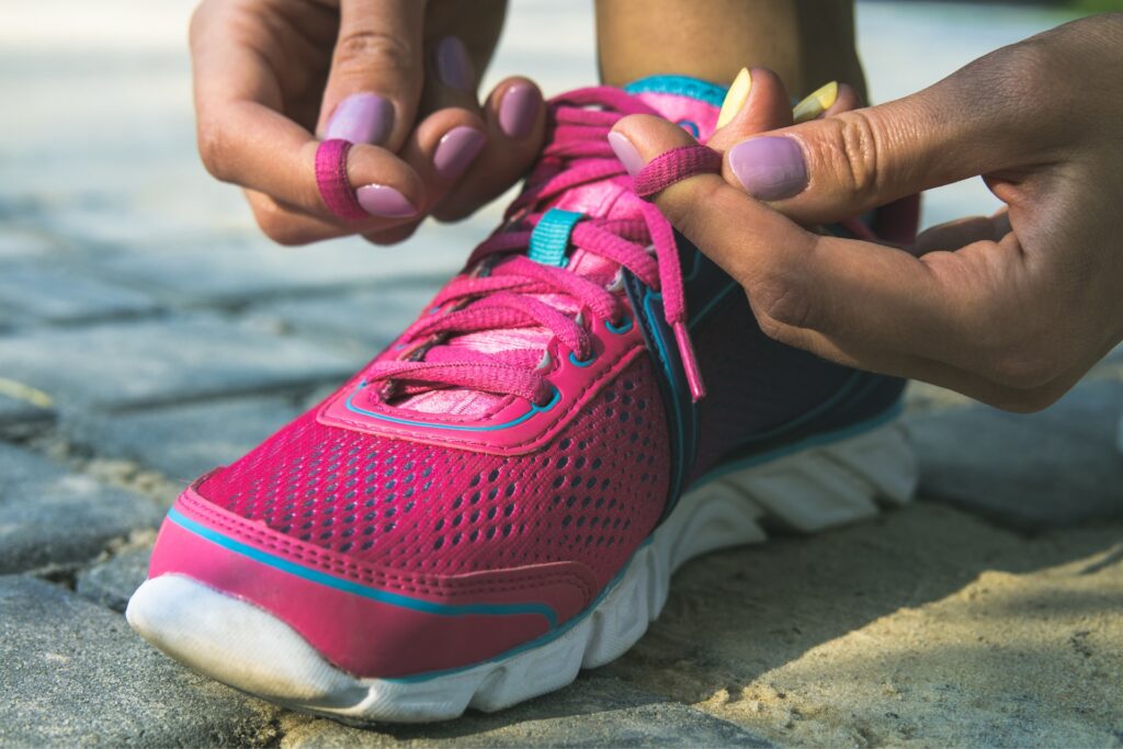 Close-up of someone tying the laces of a pink athletic sneaker.