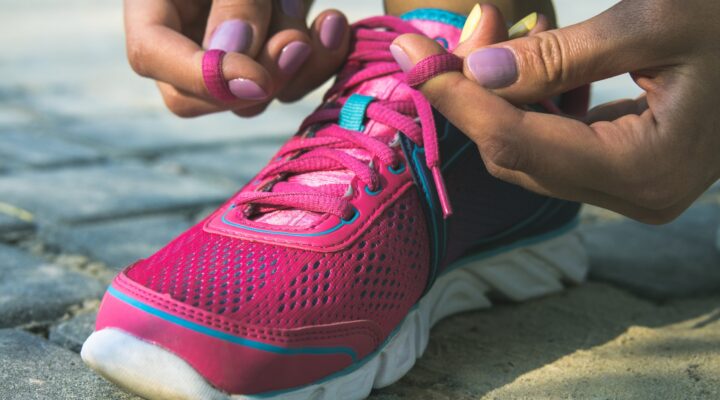 Close-up of someone tying the laces of a pink athletic sneaker.